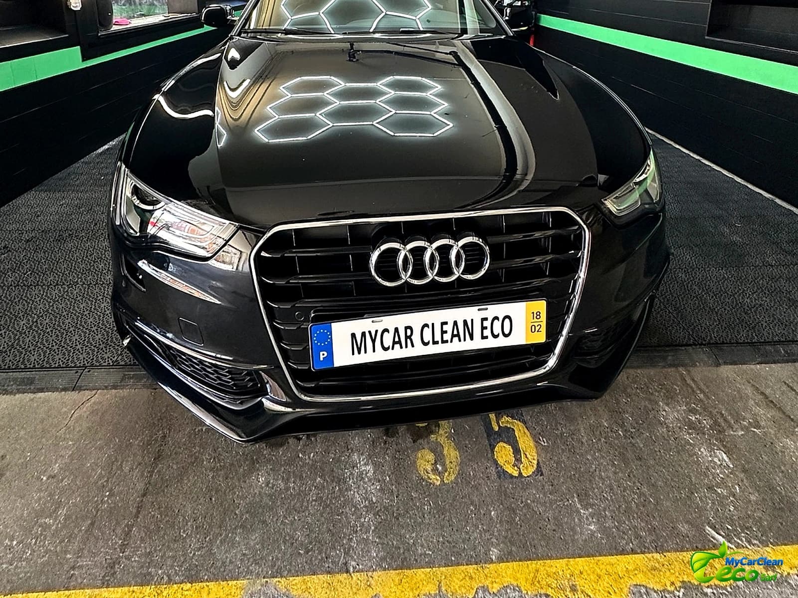 Audi noire propre dans l'atelier MyCarCleanEco, carrosserie brillante sous les lumières hexagonales